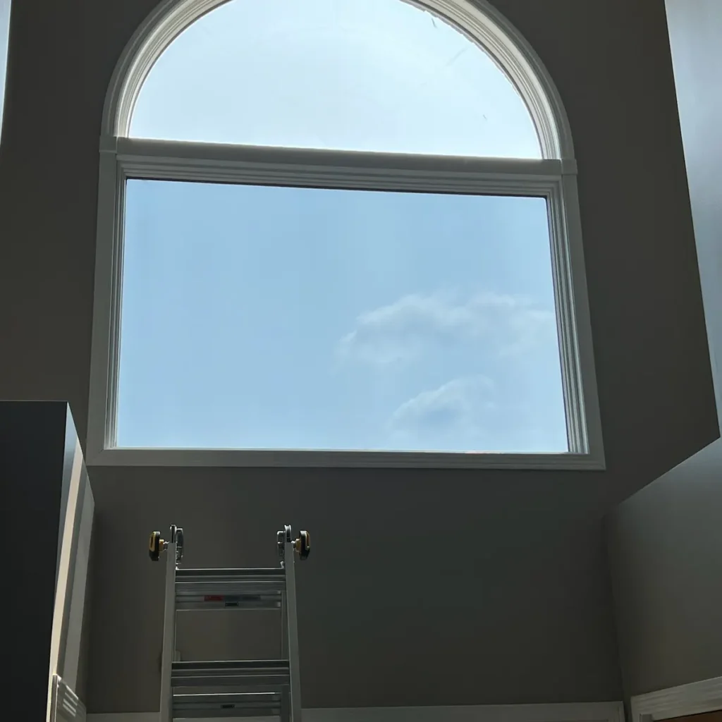Tall arched window in a two-story foyer after window film installation in St. John, IN