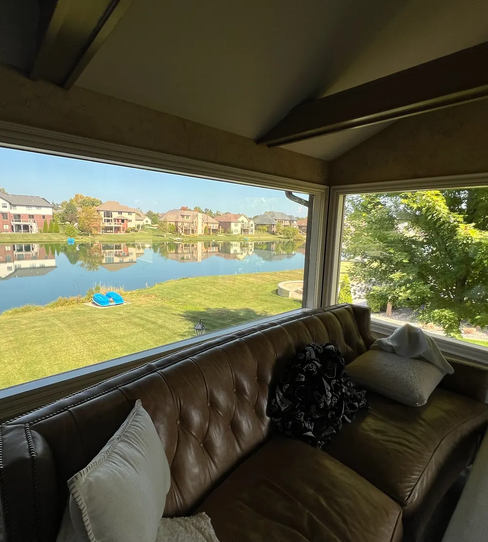 Living room picture windows overlooking a pond after residential window tinting in St. John, IN